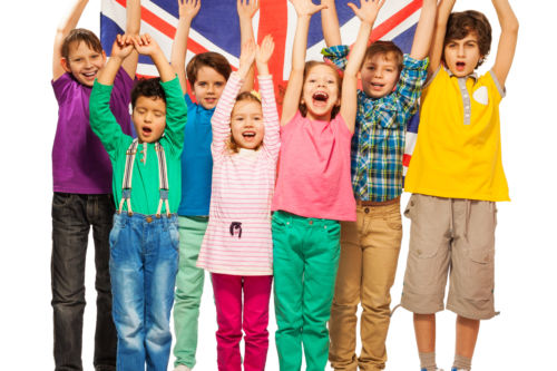 Group of seven happy kids raising their hands up with English flag, isolated on white background