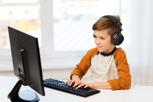 happy boy with computer and headphones at home
